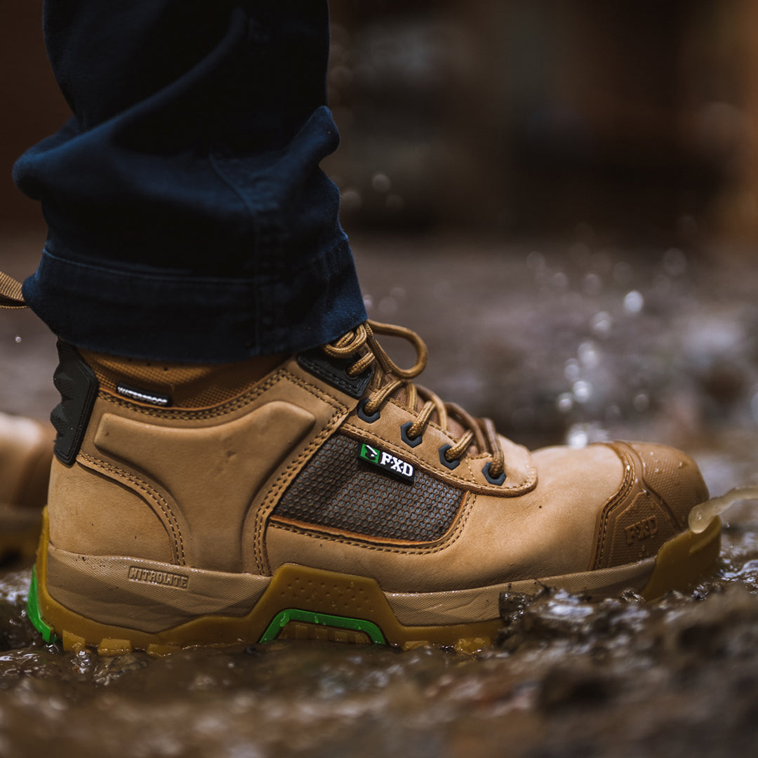 Person walking in muddy water wearing FXD waterproof work boot 1.
