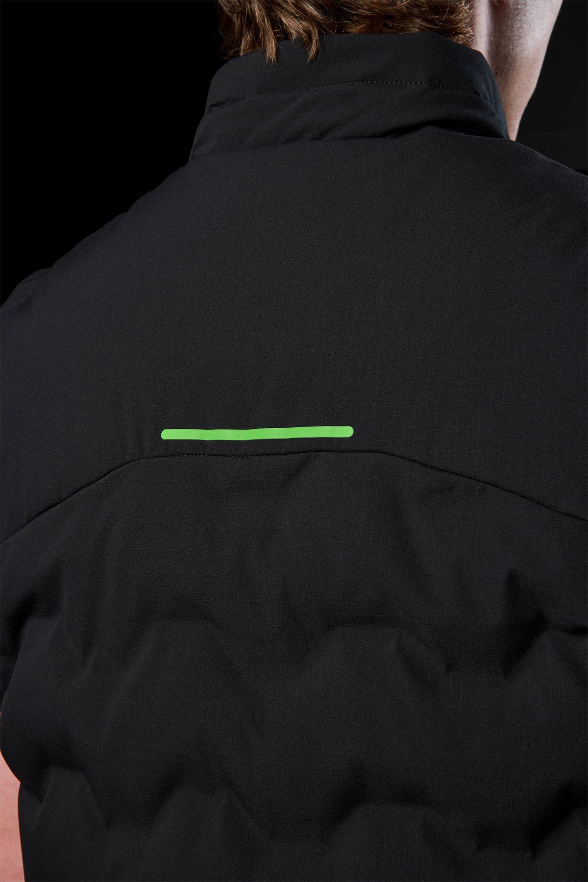 Back view of black FXD WO-6 insulated puffer vest with a neon green stripe across the upper back