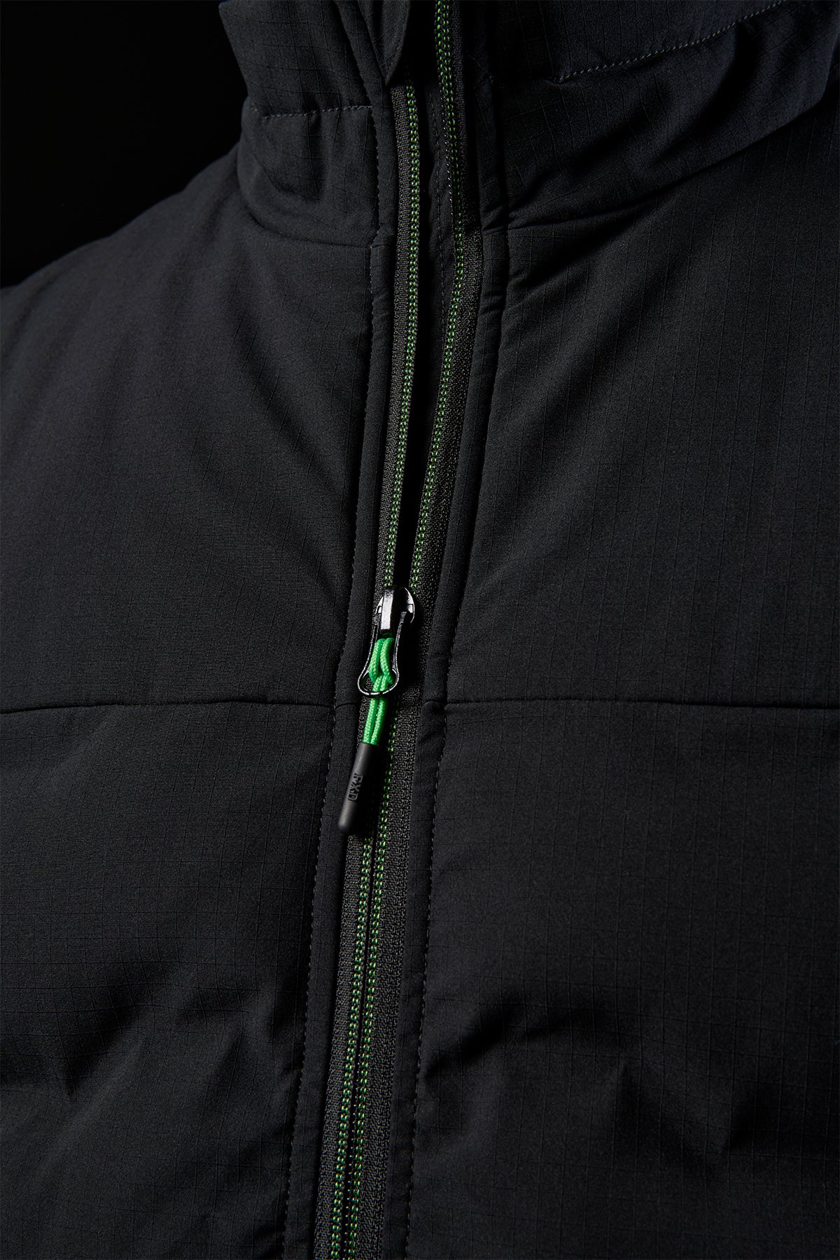Close up of the front zipper area on the black FXD WO-6 vest with a green zipper pull