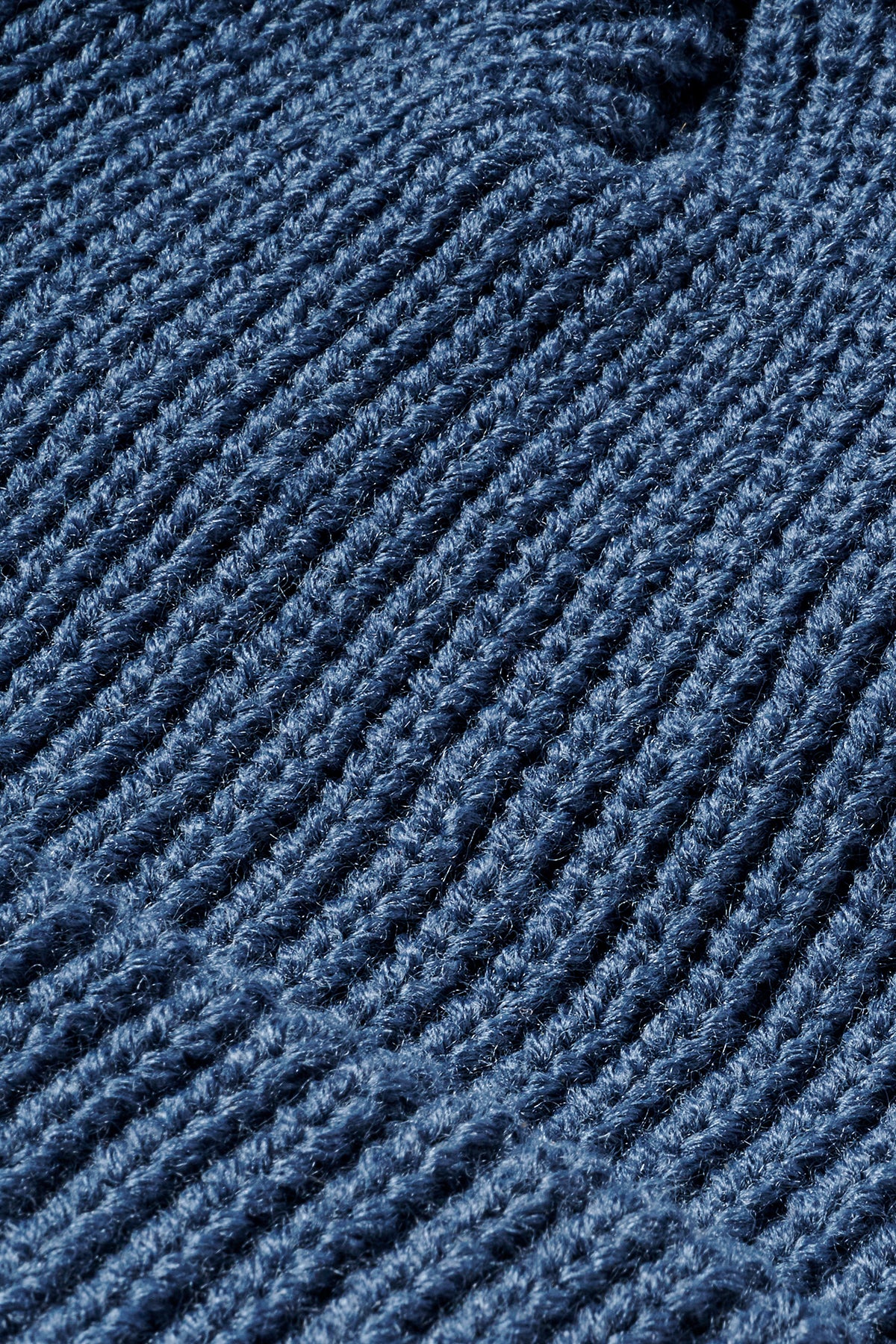 Macro shot of dense blue knit fabric detailing the CP 10 beanie