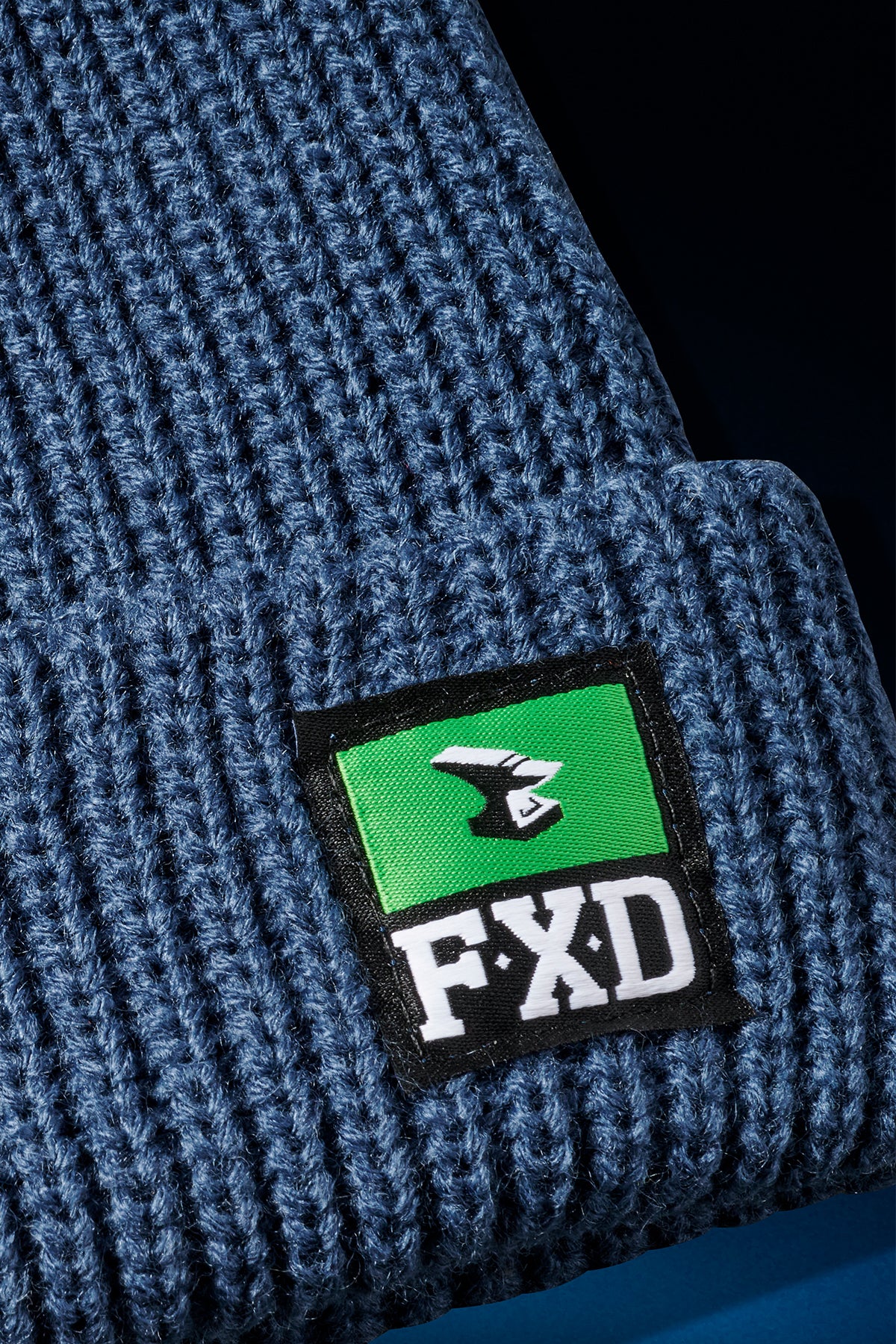 Close up of blue knit with green FXD woven label on CP 10 beanie