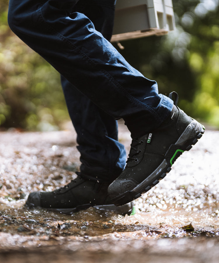 person working in muddy water wearing FXD WB2WP work boot 2 waterproof. 