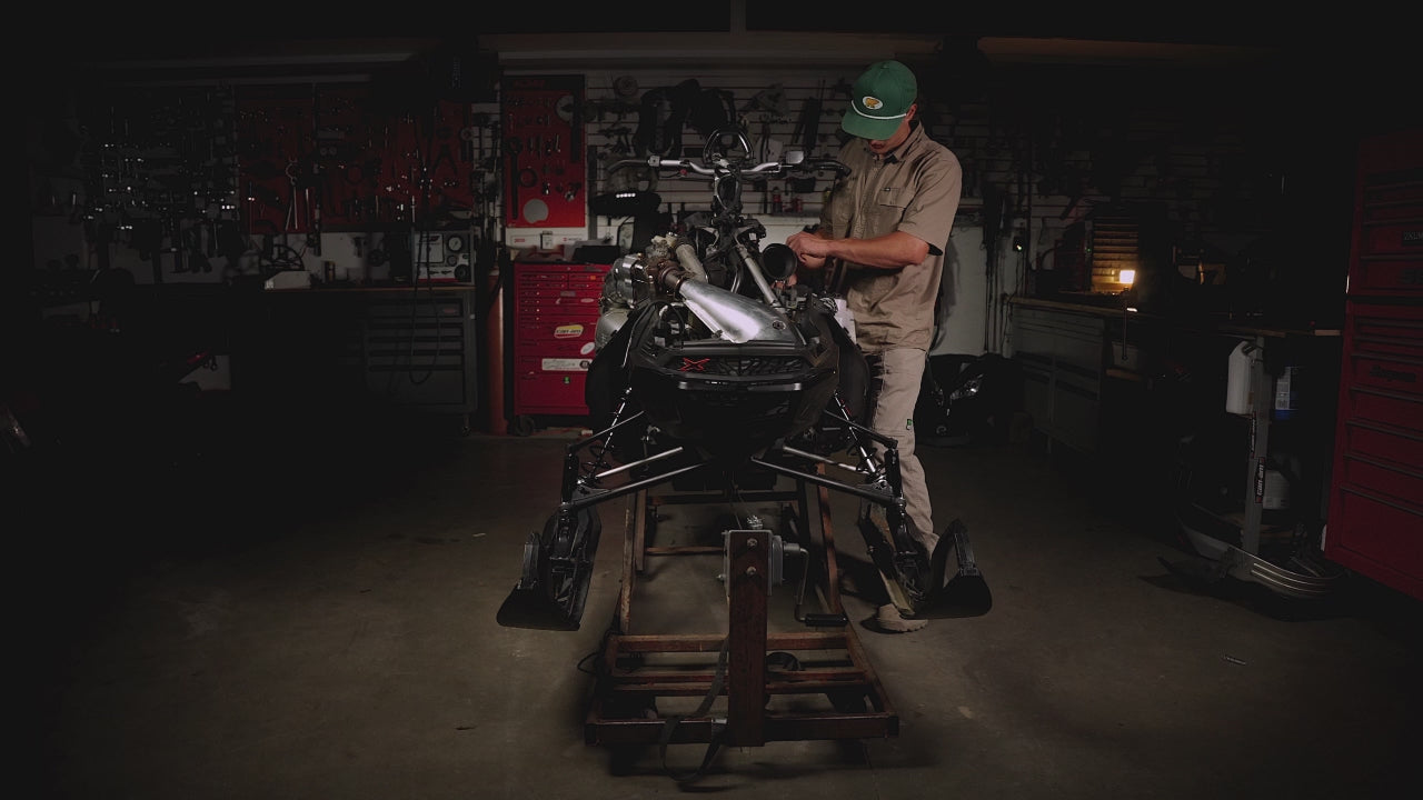 Person wearing FXD workwear while working on snow mobile